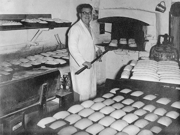 Cyril Beckett putting loaves in the oven